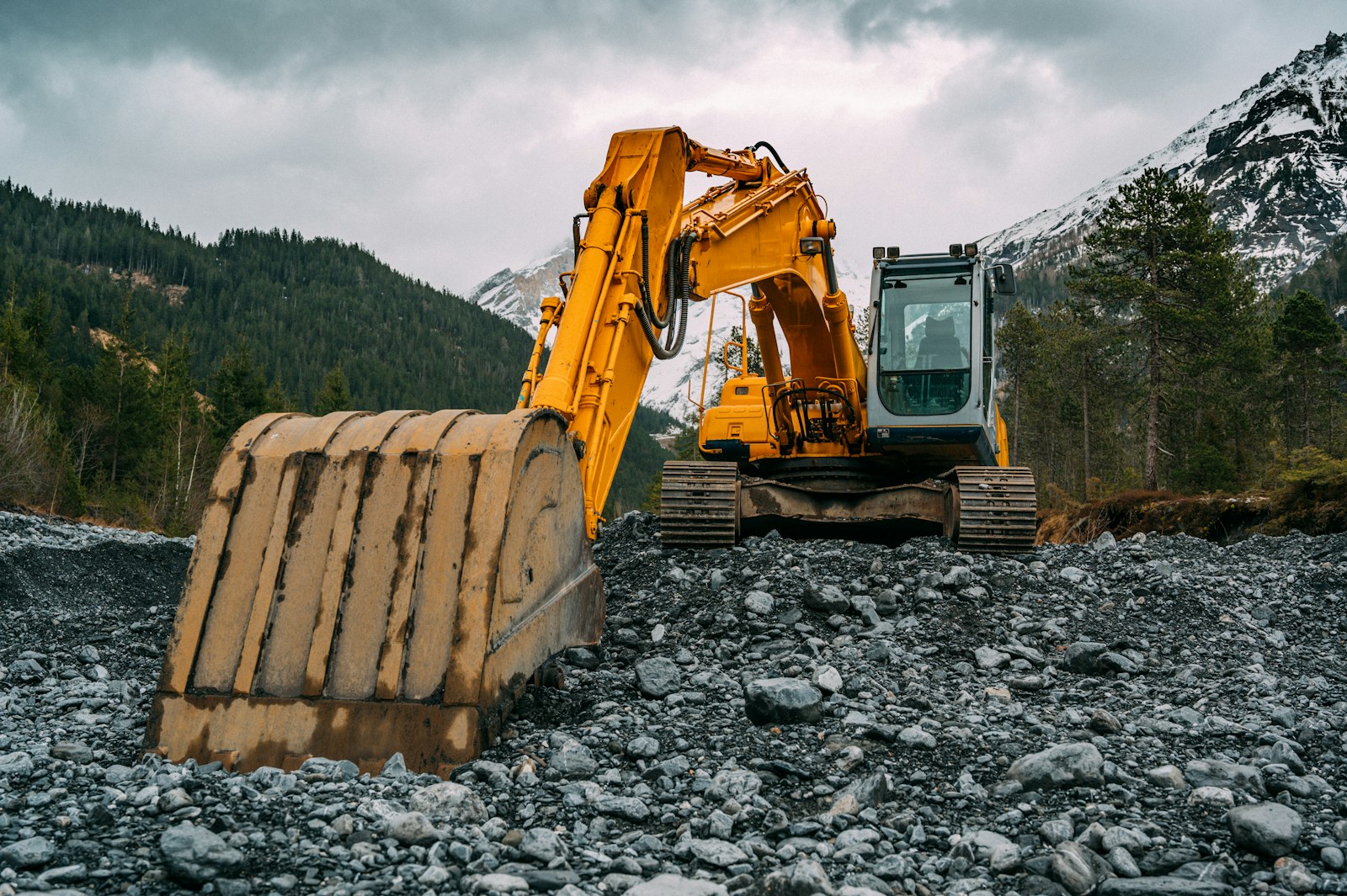 Yellow excavator working on rocky ground.