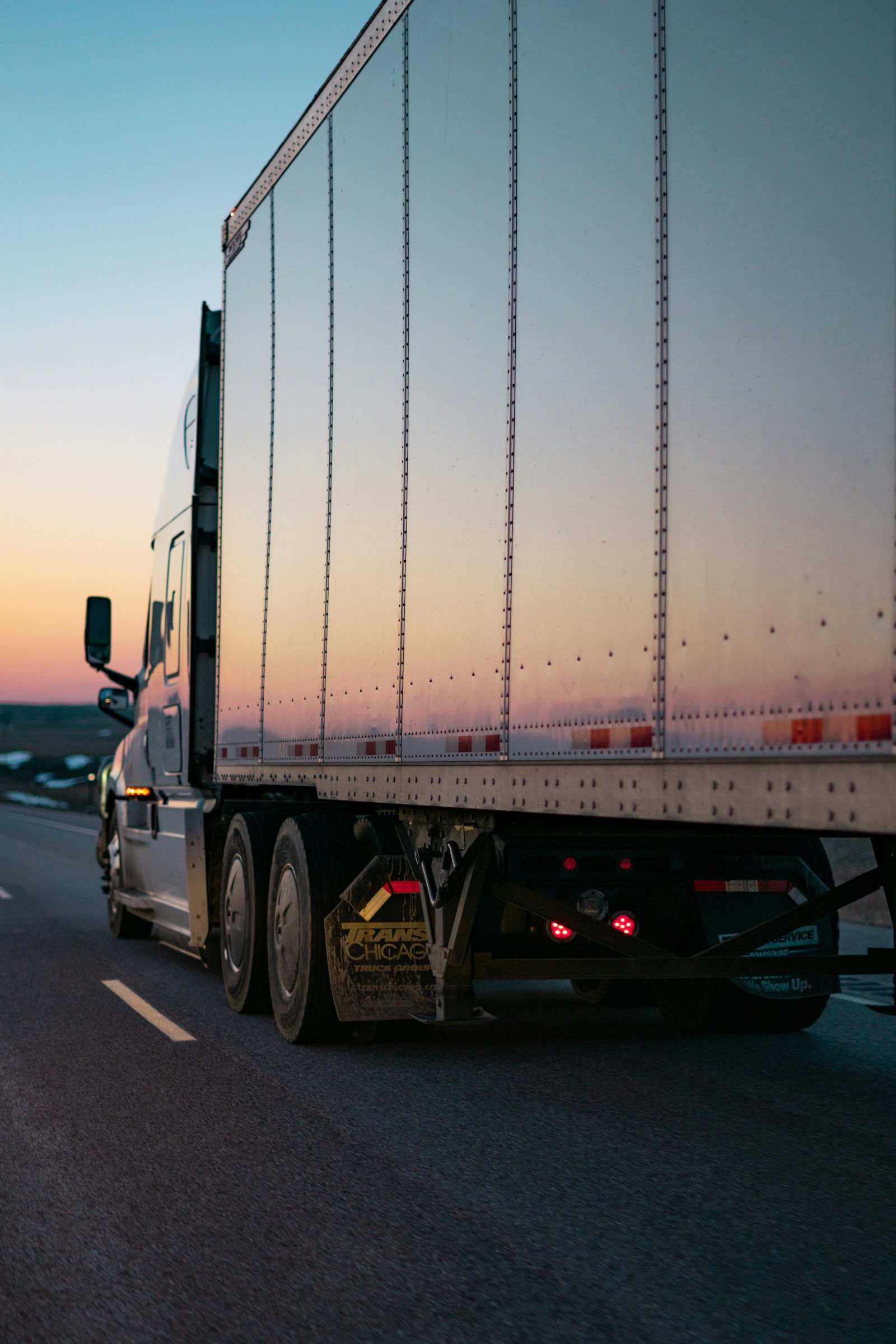White freight truck traveling on a highway.
