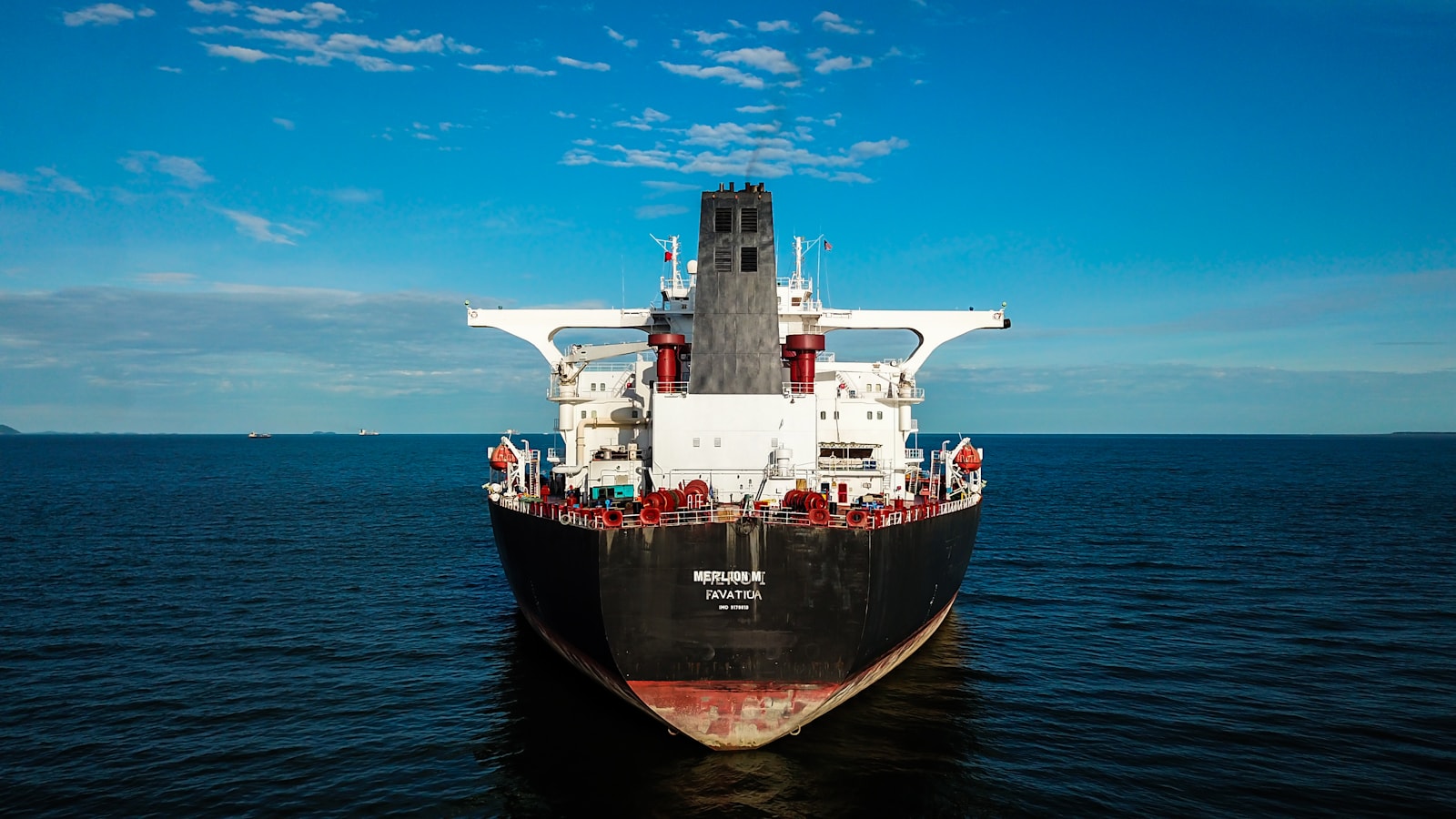 Red commercial ship operating at sea.